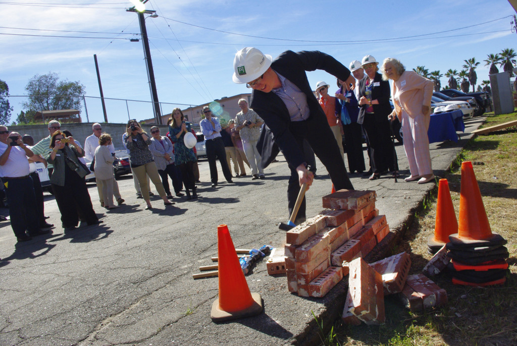 nterfaith Executive Director Greg Anglea knocks down wall at groundbreaking event.