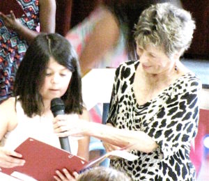 Carol Curcio helps sister of essay award winner read the winning poem .